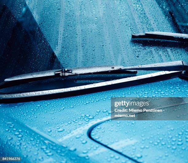 close-up of a wet windshield and dashboard of a blue car at night - ruitenwisser auto stockfoto's en -beelden