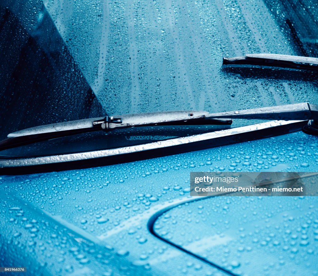 Close-up of a wet windshield and dashboard of a blue car at night