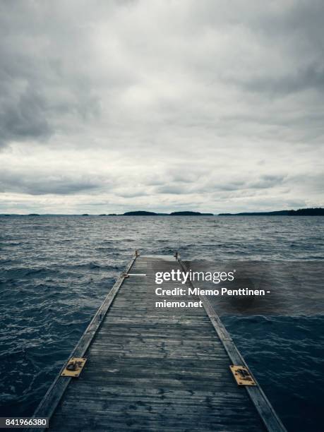 a wooden pier reaching out to lake päijänne in finland on a stormy, overcast summer day - lake finland bildbanksfoton och bilder