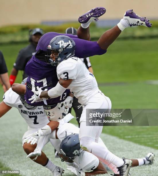 Justin Jackson of the Northwestern Wildcats flips in the air after being hit by Dameon Baber and Ahki Muhammad of the Nevada Wolf Pack at Ryan Field...
