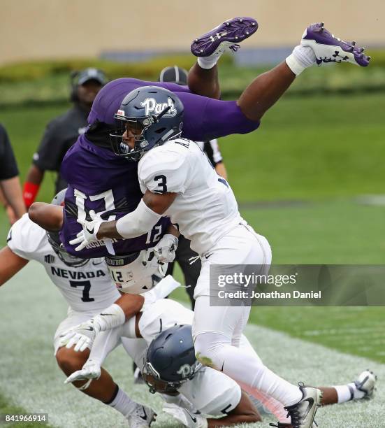 Justin Jackson of the Northwestern Wildcats flips in the air after being hit by Dameon Baber and Ahki Muhammad of the Nevada Wolf Pack at Ryan Field...