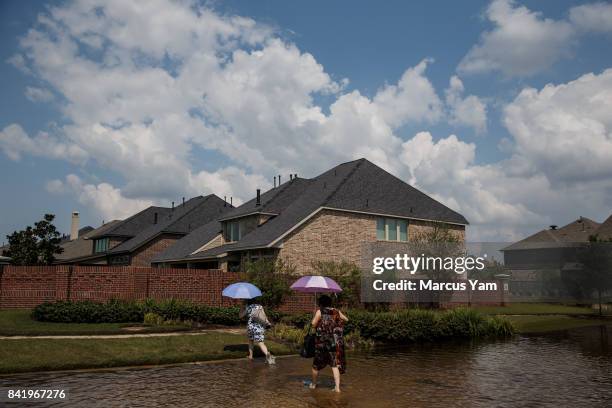 Local residents cross a flooded street in the Millwood subdivision of Fort Bend County, Texas, on Sept. 2, 2017.