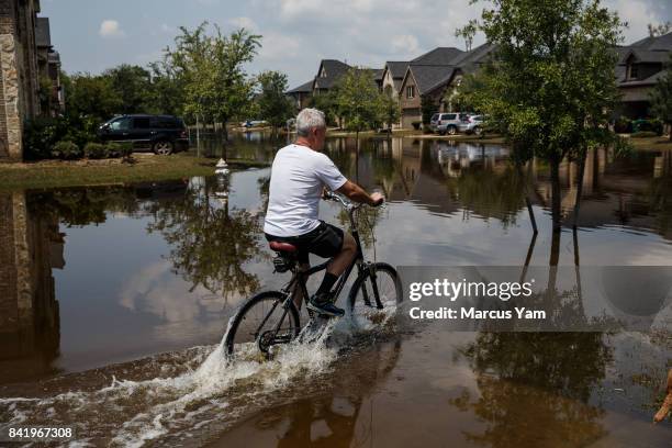 Man cycles through floodwater in the aftermath of tropical storm Harvey, in the Millwood subdivision of Fort Bend County, Texas, on Sept. 2, 2017.