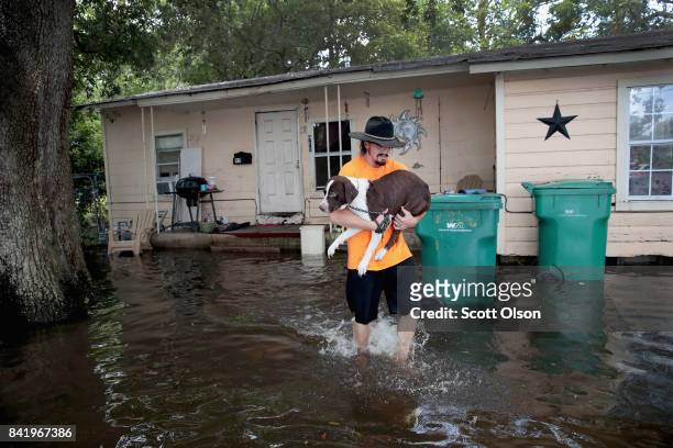 Resident carries his dog to a rescue boat from his home which is surrounded by floodwater after torrential rains pounded Southeast Texas following...