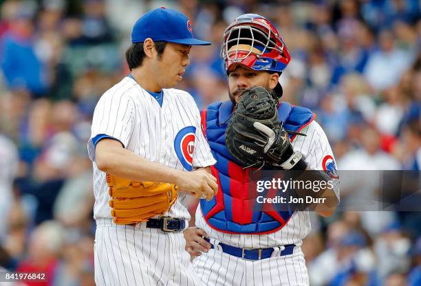 Koji Uehara of the Chicago Cubs talks with Rene Rivera during the seventh inning of their game against the Atlanta Braves at Wrigley Field on...