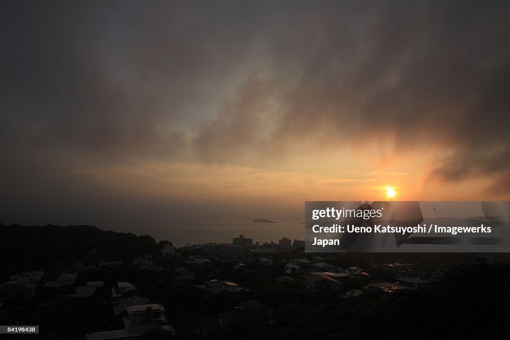 Japan, Kanagawa Prefecture, Zushi City, Sunset over sea with buildings in foreground