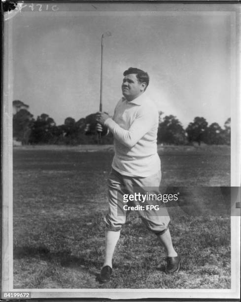 American baseball player Babe Ruth plays golf on an unidentified course, early 1920s.