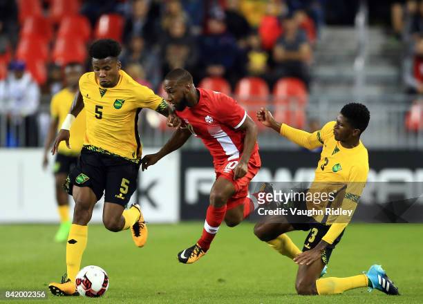 David Junior Hoilett of Canada is tackled by Alvas Powell and Damion Lowe of Jamaica during the second half of an International Friendly match at BMO...