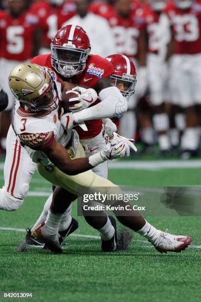 Cam Akers of the Florida State Seminoles is tackled by Ronnie Harrison of the Alabama Crimson Tide during their game at Mercedes-Benz Stadium on...