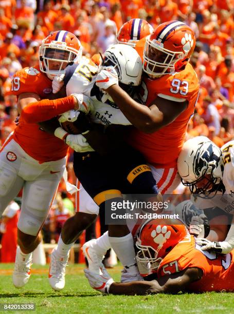 Tailback Will Matthews of the Kent State Flashes is taken down by safety Tanner Muse and defensive tackle Sterling Johnson of the Clemson Tigers of...