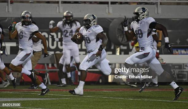Linebacker Devin Rollins of the Howard Bison is flanked by defensive back Bryan Cook and linebacker Elijah Anglin as Rollins returns a recovered...