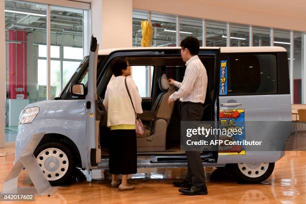 This picture taken on July 20, 2017 shows 75-year-old flower shop owener Yoko Kojima talking with a salesman at the Daihatsu car dealer in Tokyo....