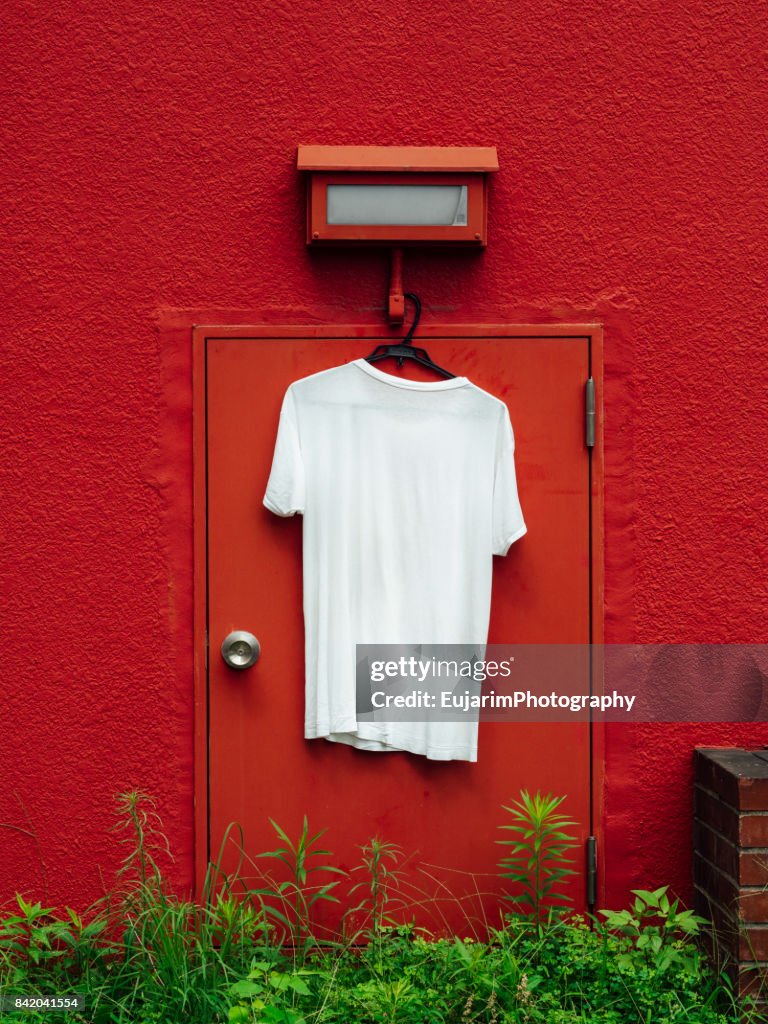 White T-shirt hangs on the red wall