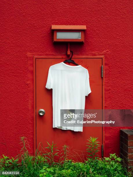 white t-shirt hangs on the red wall - plain t shirt stock pictures, royalty-free photos & images