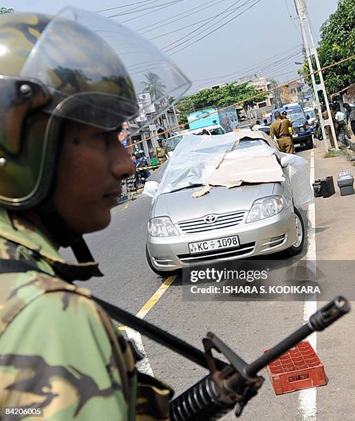 Sri Lankan soldier stands guard in front of the damaged car of newspaper editor Lasantha Wickrematunga, in the suburbs of Colombo on January 8, 2009....