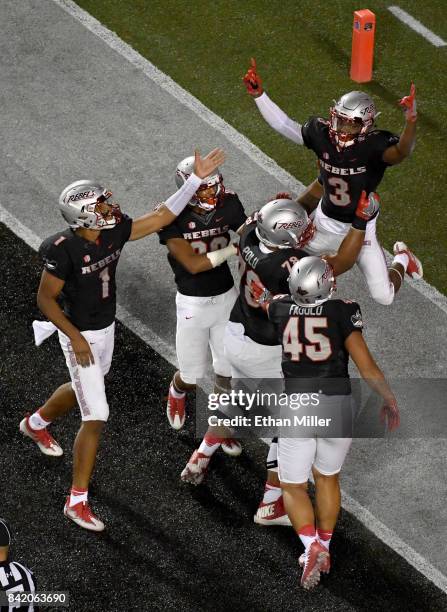 Running back Lexington Thomas of the UNLV Rebels celebrates in the end zone with teammates including quarterback Armani Rogers after scoring on a...