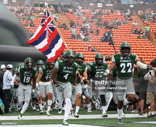 The University of Hawaii Rainbow Warriors run on the the field before their first home game of the season against the Western Carolina Catamounts at...