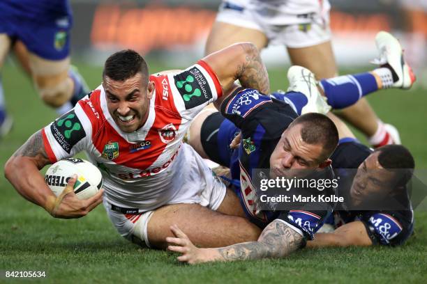 Paul Vaughan of the Dragons is tackled by David Klemmer and Moses Mbye of the Bulldogs during the round 26 NRL match between the St George Illawarra...