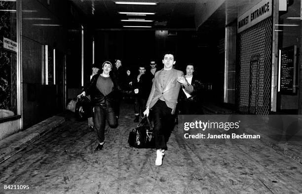 Lead vocalist Kevin Rowlands leads other members of the band Dexys Midnight Runners in a charge through one of London's market spaces, 1980.