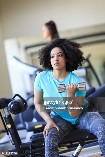 afrikaanse vrouw training met halters in fitness - bicep curl stockfoto's en -beelden