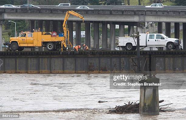 Railroad workers replace ties above a swollen Puyallup River January 8, 2009 in Tacoma, Washinigton. Record rain and snow has caused many rivers in...