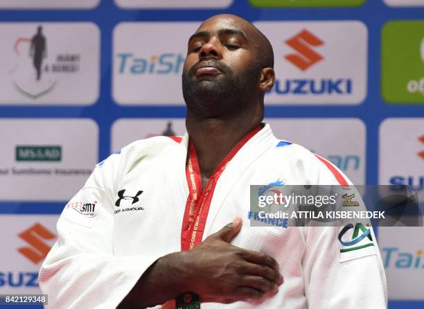 Gold medalist France's Teddy Riner listens to his national anthem as he celebrates on the podium after winning the mens +100kg category at the World...