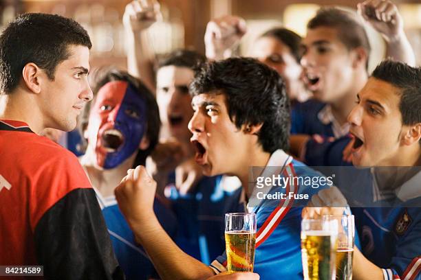 group of soccer fans cheering in bar - rivaliteit stockfoto's en -beelden