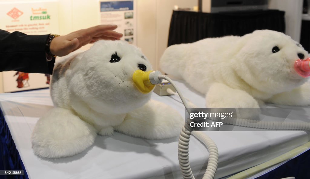 A man pets a Paro therapeutic robot on d