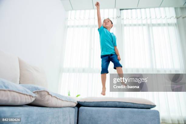 little boy jumping on sofa - drapeado stock pictures, royalty-free photos & images