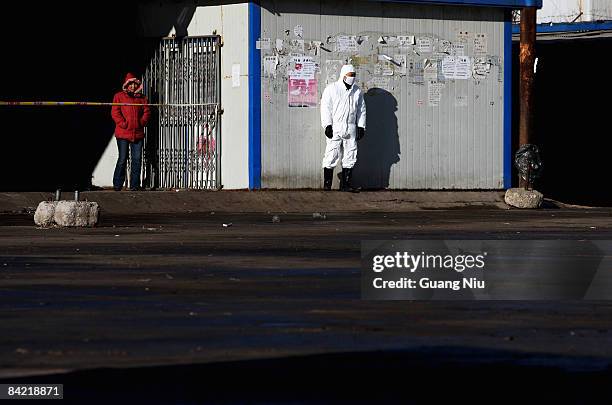 Chinese policeman and a woman stand outside a disinfected the isolated plot of a poultry market on January 9, 2009 in Yanjiao, north China's Hebei...