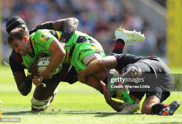 Nic Groom of Northampton Saints is tackled by Schalk Brits and Maro Itoje of Saracens during the Aviva Premiership match between Saracens and...