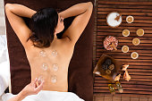 Relaxed Young Woman Receiving Cupping Treatment On Back