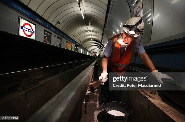 Worker cleans the ceramic insulator pots under the live rail at Pimlico Underground Station on October 6, 2008 in London. A team of four cleaners...