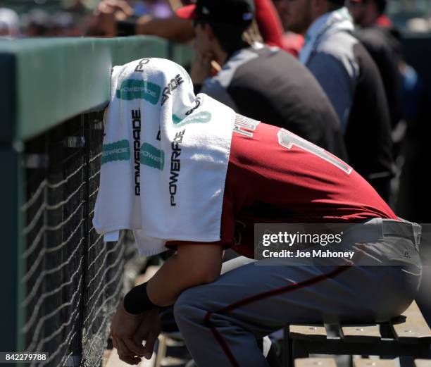 Reymond Fuentes of the Arizona Diamondbacks covers his head with a towel in the dugout and watches the first inning of the Diamondbacks game against...