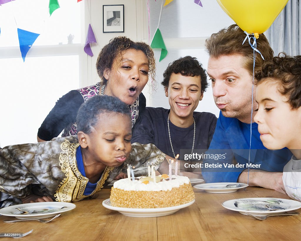 Family blowing out birthday cake candles.