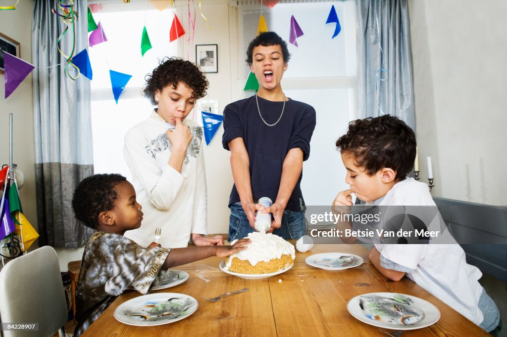 Siblings sitting around birthdaycake