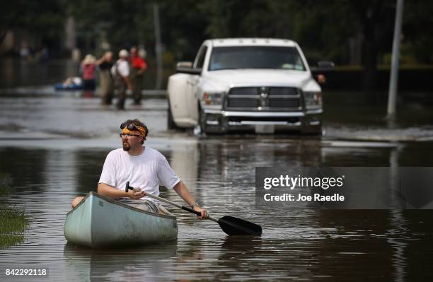 Paul steers his canoe as he looks to help people retrieve items out of homes that were inundated with water in an area where a mandatory evacuation...