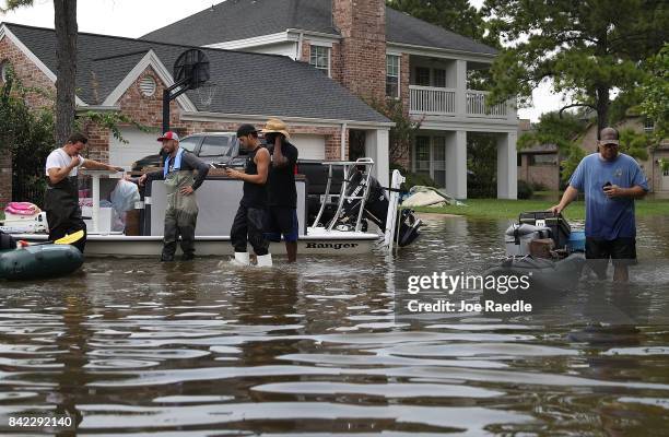 People use boats to help bring items out of homes in an area where a mandatory evacuation is still under effect after flood water inundated them...