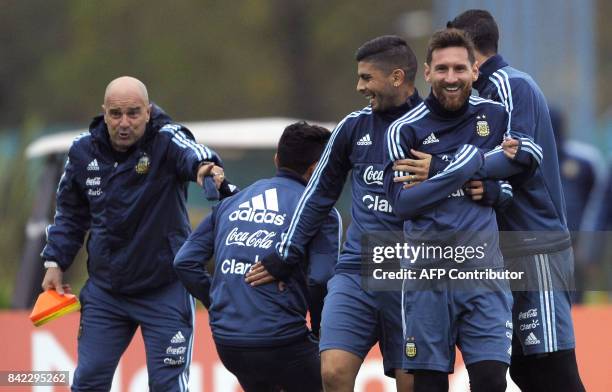 Argentina's forward Lionel Messi , midfielder Ever Banega and midfielder Angel Di Maria joke around during a training session in Ezeiza, Buenos Aires...