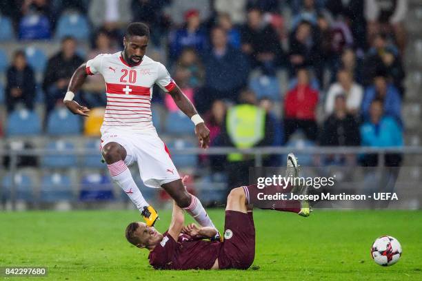 Johan Djourou of Switzerland is tackled by Aleksejs Visnakovs of Latvia during the FIFA 2018 World Cup Qualifier between Latvia and Switzerland at...