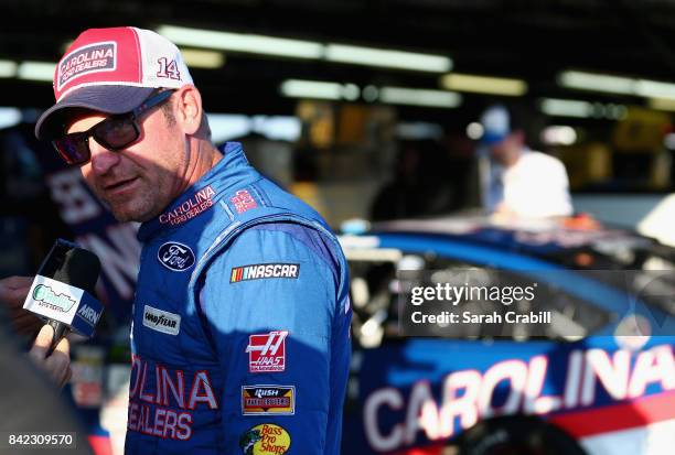 Clint Bowyer, driver of the Carolina Ford Dealers Ford, speaks with the media in the garage area after his engine expired during the Monster Energy...