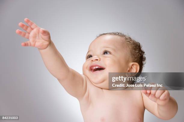 curious mixed race baby boy with arm raised - baby reaching stock pictures, royalty-free photos & images