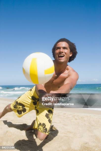 african man playing volleyball at beach - beach volleyball stockfoto's en -beelden