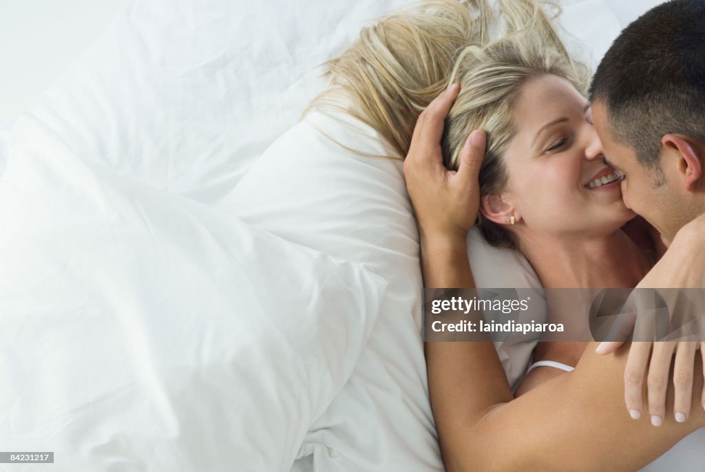 Smiling Hispanic couple laying in bed