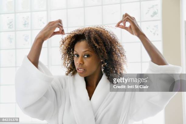 african woman pulling frizzy hair in bathroom - morgens anziehen stock-fotos und bilder