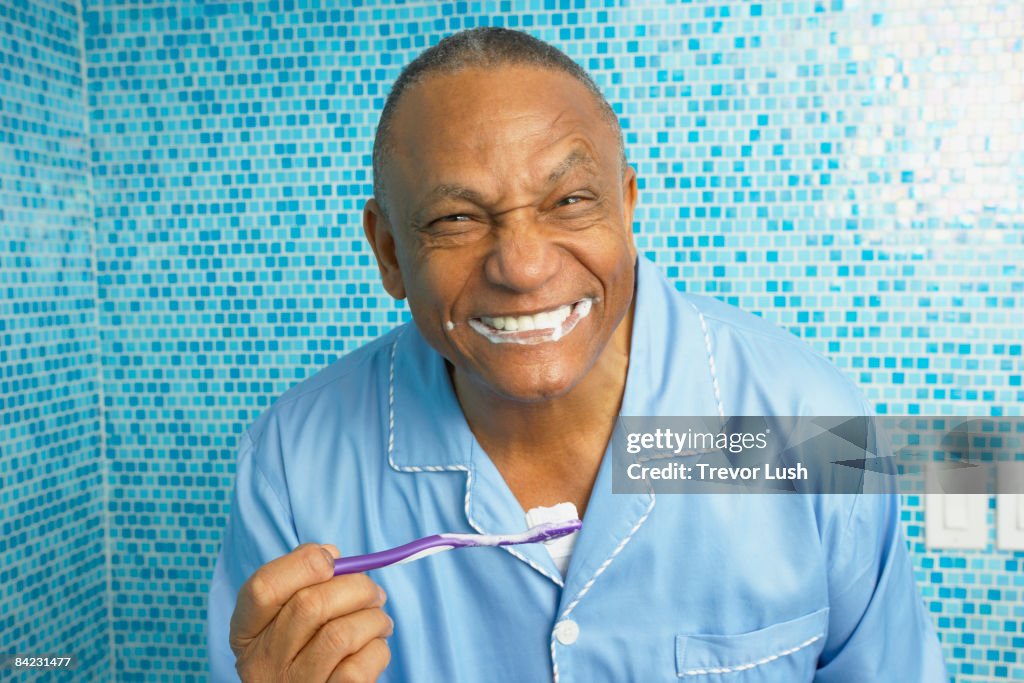 African man brushing his teeth in bathroom