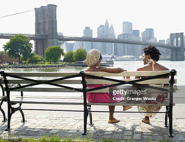 african women sitting on bench at urban waterfront - lower east side manhattan stock pictures, royalty-free photos & images