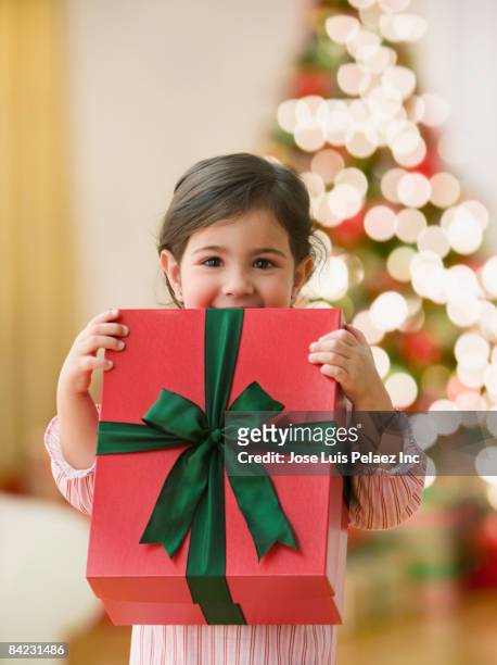 curious young girl holding large christmas gift - before christmas stock-fotos und bilder