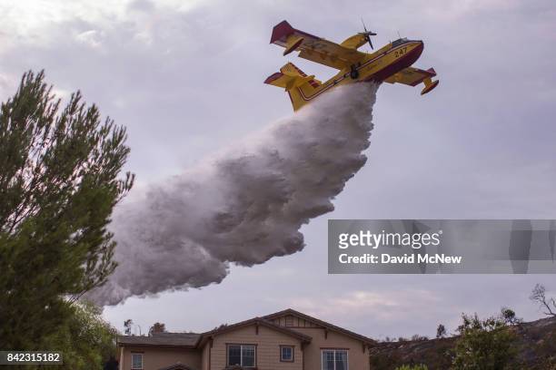Super Scooper CL-415 firefighting aircraft from Canada makes a drop to protect a house during the La Tuna Fire on September 3, 2017 near Burbank,...
