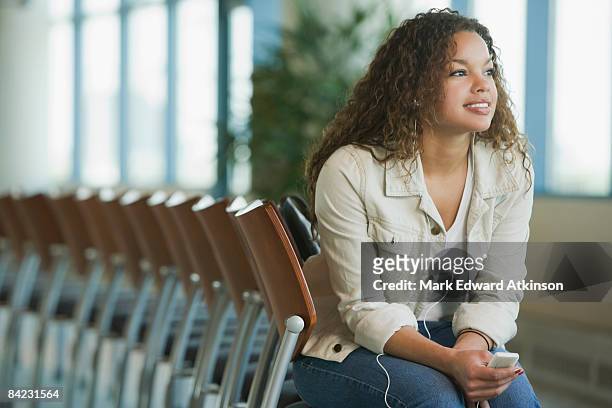 african woman listening to mp3 player waiting in airport - atkinson mp stock pictures, royalty-free photos & images